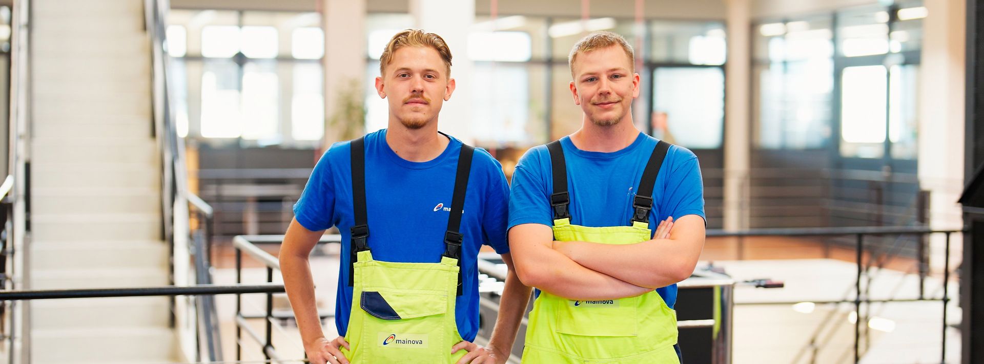 wei Personen in Arbeitskleidung gehen durch eine technische Anlage mit großen Maschinen.