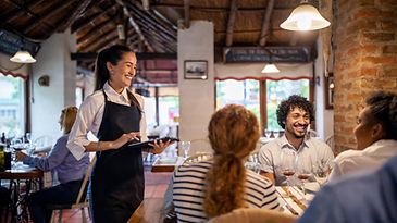 Eine freundliche Kellnerin nimmt die Bestellung der Gäste auf.