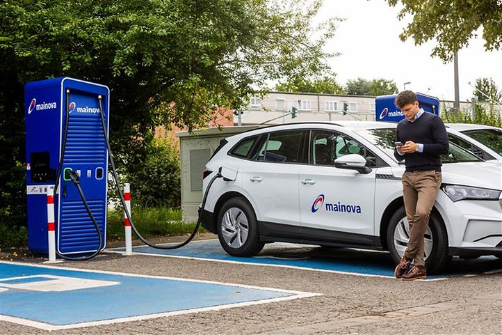 Mann steht vor einem E-Auto, dass gerade lädt