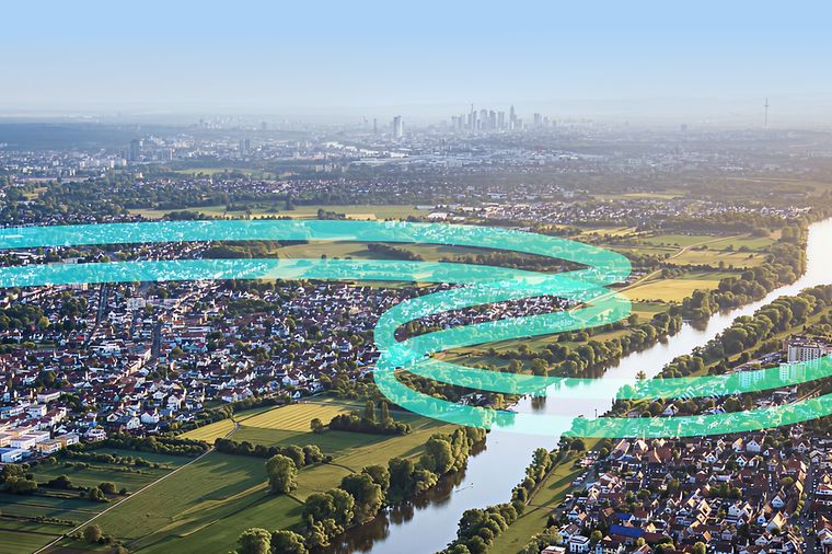 Flusslandschaft aus der Luft mit Stadt, Feldern und grafischen Linien zur Darstellung von Energieflüssen.