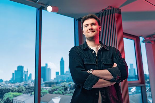 man mit verschränkten Armen lächelt in die Kamera