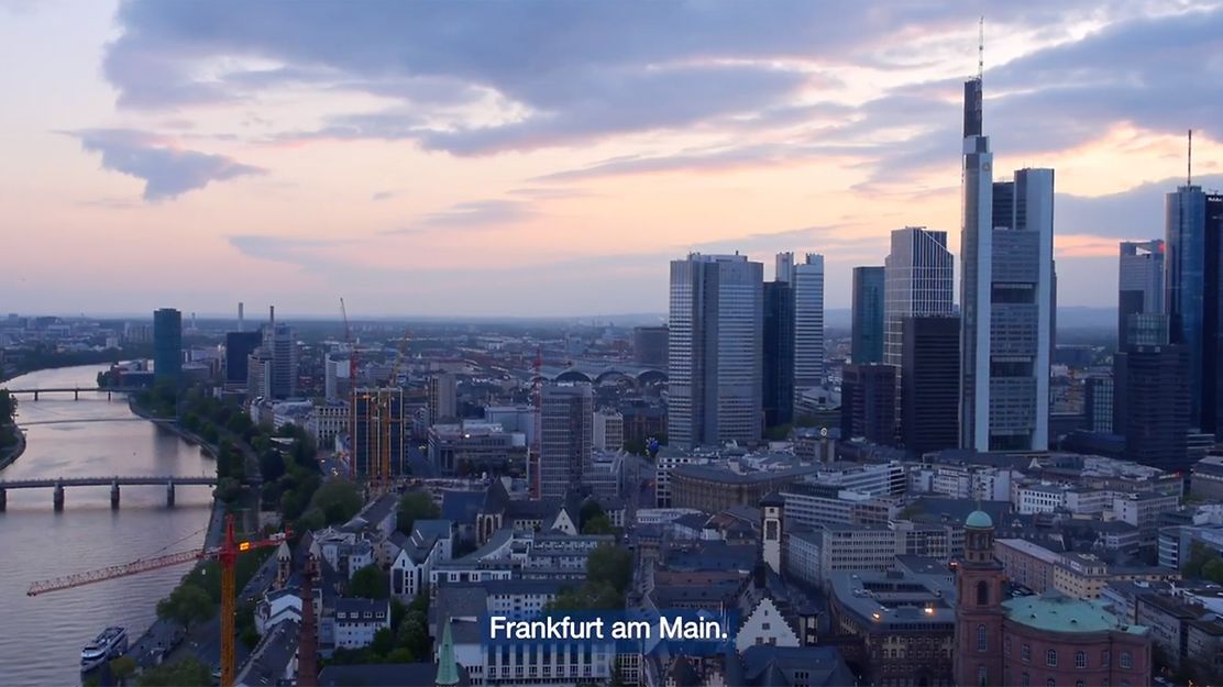 Panoramablick auf die Frankfurter Skyline mit Main, Hochhäusern und Abendhimmel in der Dämmerung.