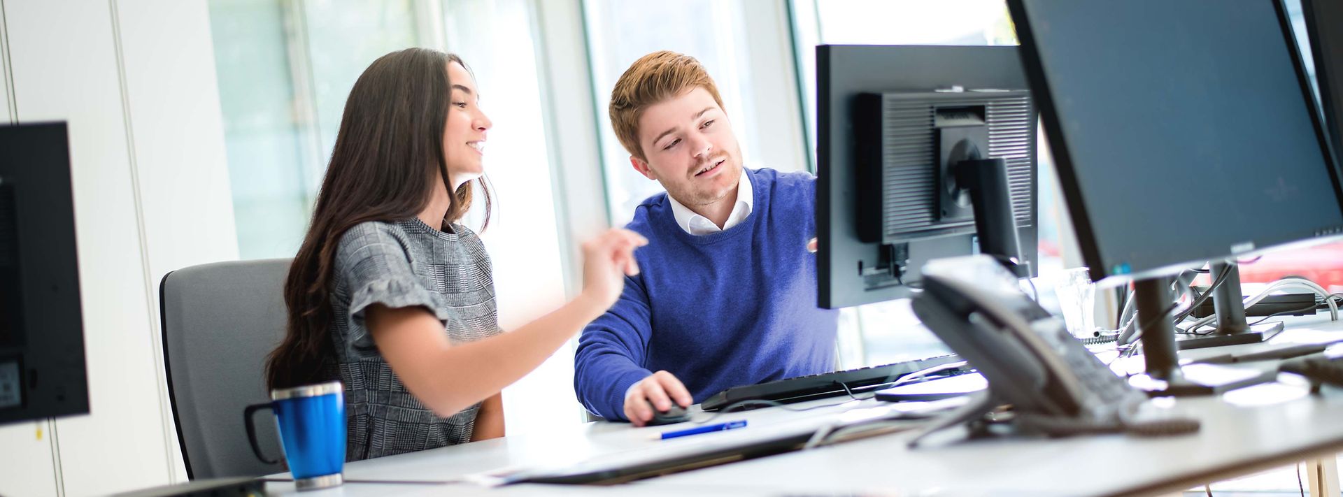 Zwei Studierende sitzen am Monitor und besprechen den Sachverhalt am Monitor