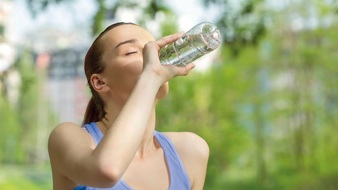 Joggende Frau trinkt aus einer Wasserflasche