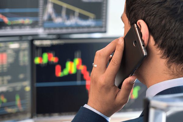 Mann am Handy vor Bildschirmen