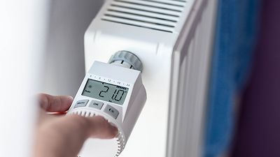 Hand programmiert ein Thermostatventil an einer Heizung