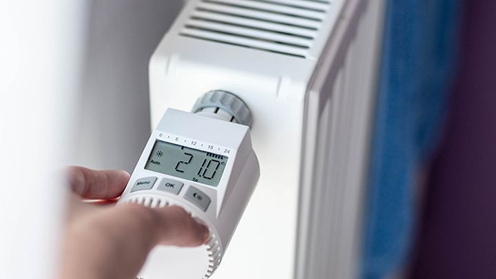 Hand programmiert ein Thermostatventil an einer Heizung