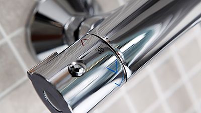 Einhebelmischer mit Thermostat, Aufschrift 38° sowie rote und blaue Pfeile als Warm-Kalt-Kennzeichnung