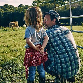 © iStock.com/pixdeluxe Vater und Tochter beobachten Kühe auf einer Weide