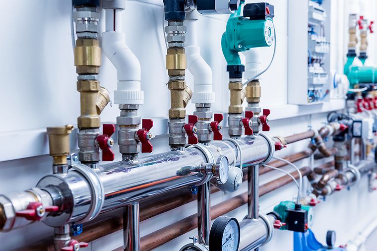 Das Bild zeigt ein komplexes Rohrleitungssystem mit verschiedenen Ventilen, Rohren und Messgeräten.