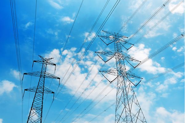 Zwei Freileitungsmasten vor blauem Himmel