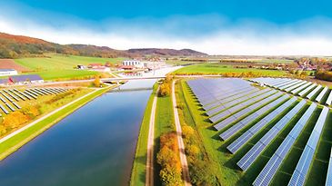 Grüne Felder mit Fluss und Photovoltaikanlagen aus der Vogelperspektive