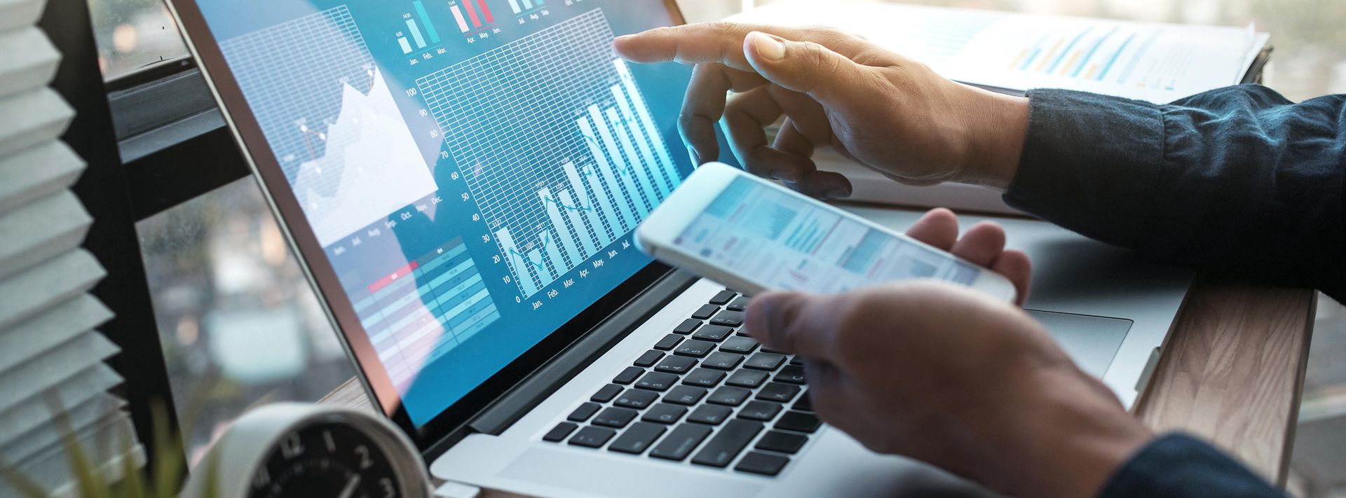 Finger einer Hand zeigt auf den Monitor eines aufgeklappten Laptops