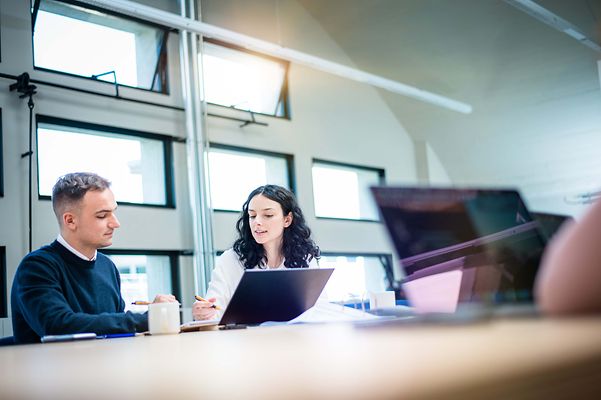 Auszubildene erklärt Kollegen am Notebook etwas