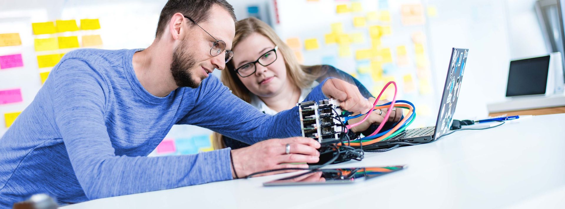 © Mainova/AndreFormer Ausbilder erklärt Auszubildende ein elektronisches Gerät was auf dem Tisch liegt