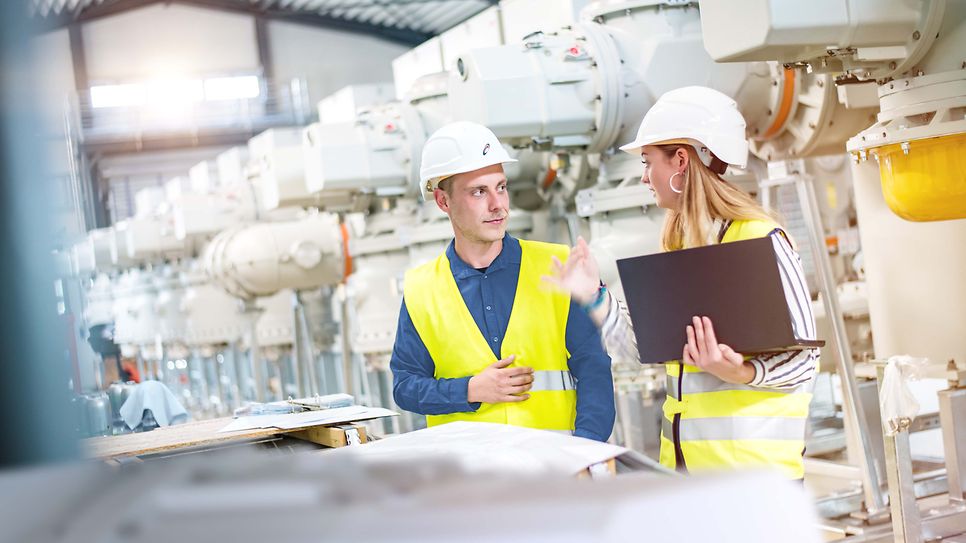 Zwei Studierende im Maschinenraum unterhalten sich vor einem Plan