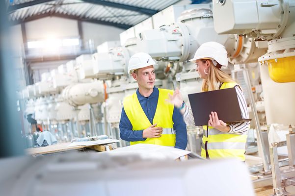Zwei Studierende im Maschinenraum unterhalten sich vor einem Plan
