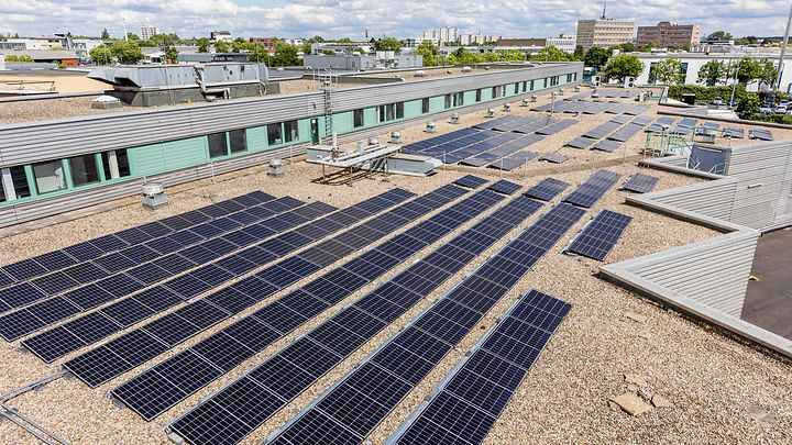 Auf einem Flachdach sind zahlreiche Solarpaneele installiert, die Sonnenenergie in Strom umwandeln.