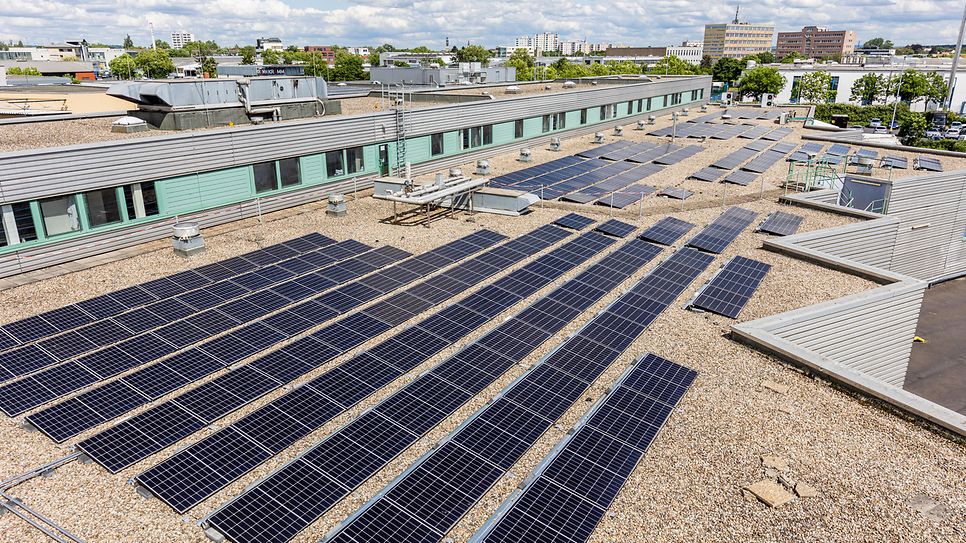 Auf einem Flachdach sind zahlreiche Solarpaneele installiert, die Sonnenenergie in Strom umwandeln.